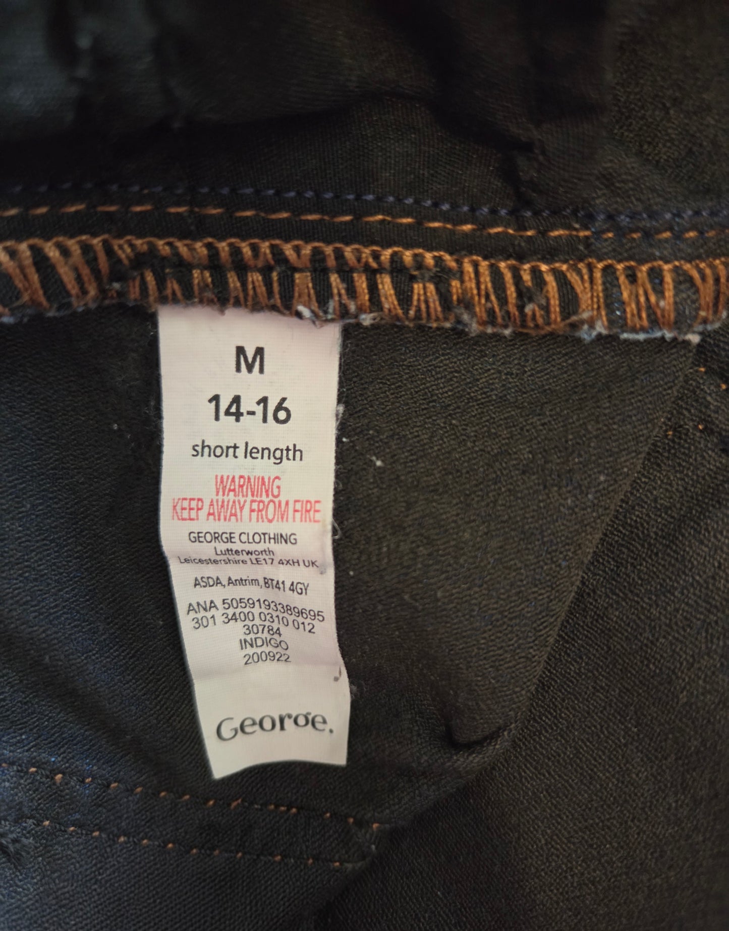 Clothing tag on a dark fabric with brand name 'George'.