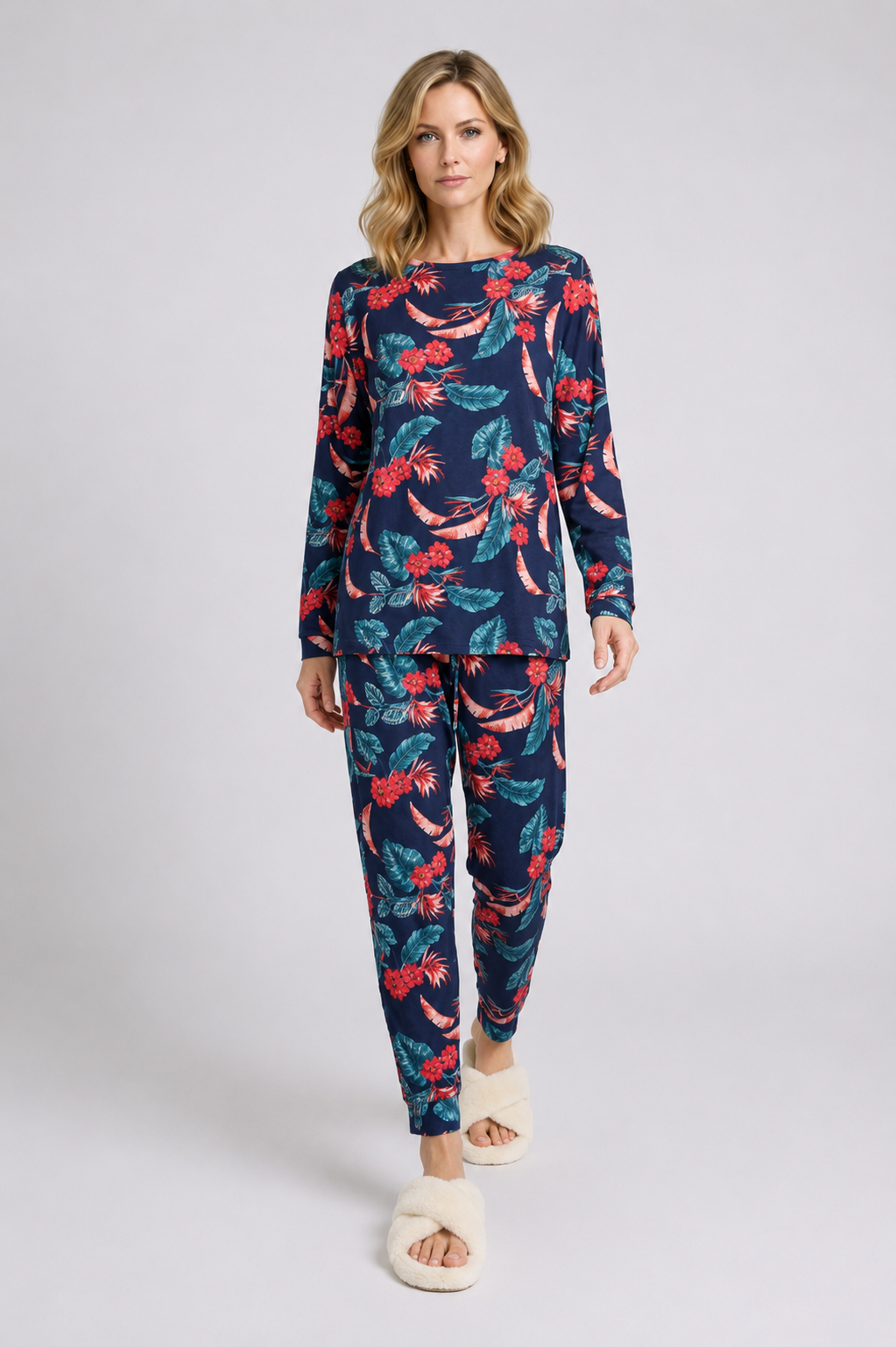 Woman wearing a navy blue pajama set with red and green floral pattern 